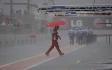 A Ferrari mechanic crosses the pit lane under heavy rain before the morning scheduled free practice for Brazil's F1 Grand Prix at the Interlagos race track in Sao Paulo, Saturday, Oct. 17, 2009. (AP Photo/Silvia Izquierdo)